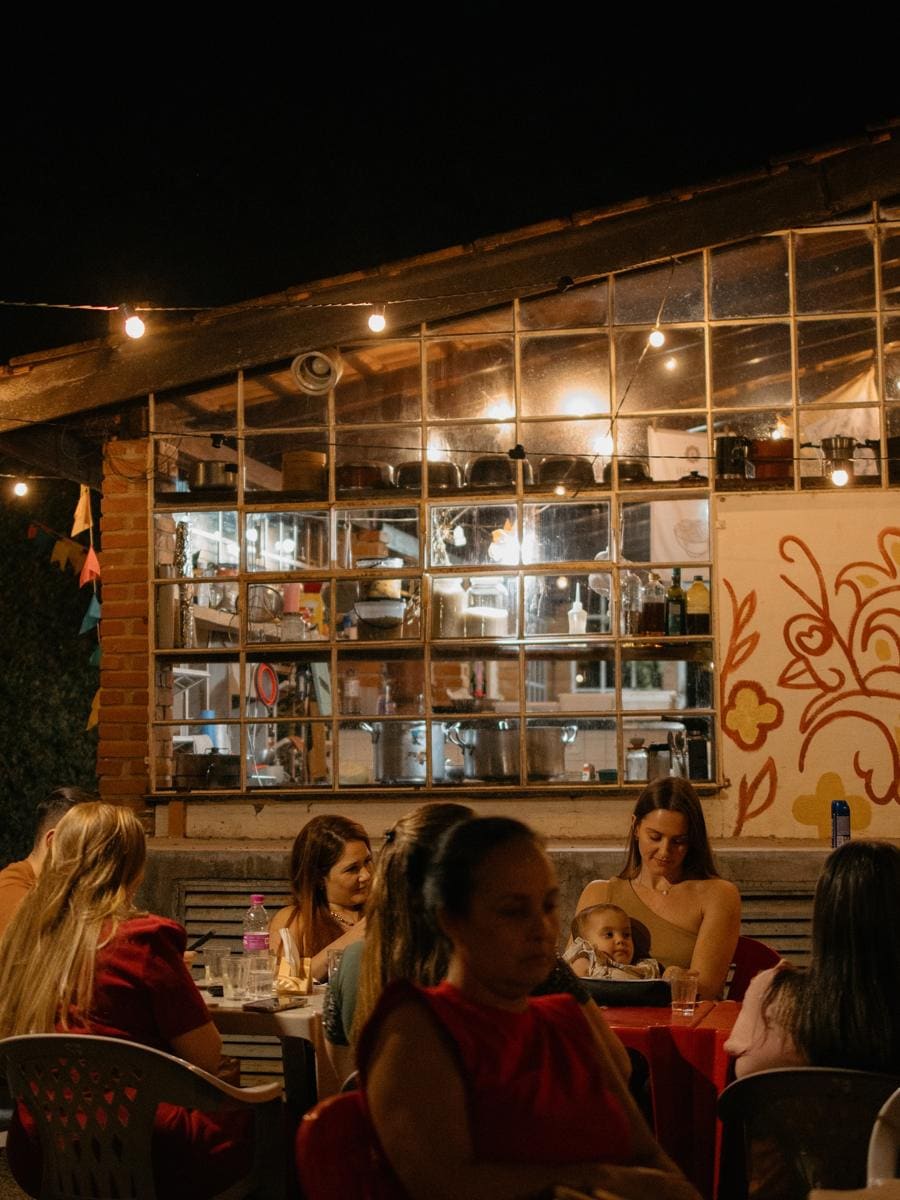 O quintal à noite, com as mesas e o varal de lâmpadas acesas